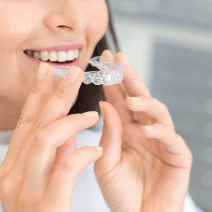 Dental Treatment Concept. Cropped image of young woman holding invisible braces, whitening tray, free space